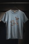 Blue t-shirt with embroidered designs on a hanger against a dark background